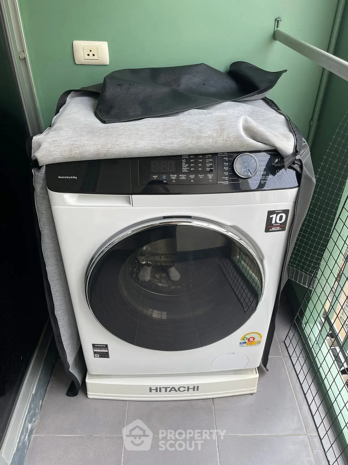 Modern Hitachi washing machine on a balcony with green walls and tiled floor.