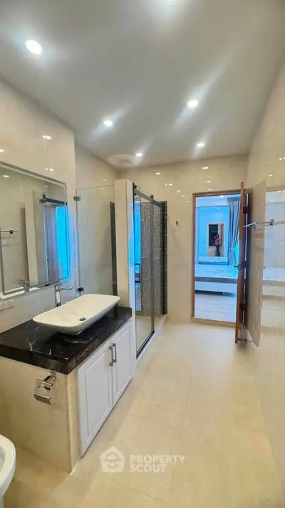 Spacious modern bathroom with glass shower and elegant vanity in luxury home.