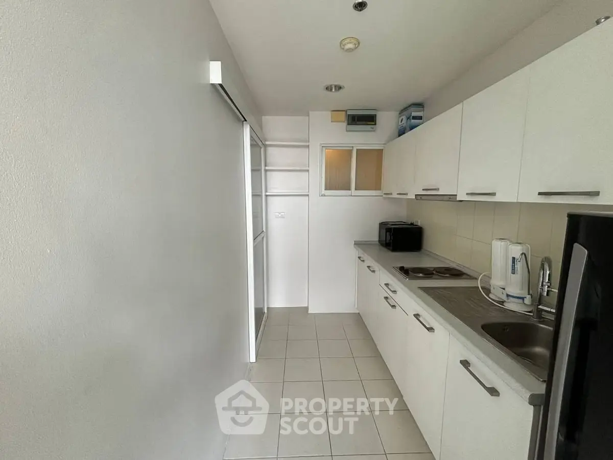 Modern kitchen with sleek white cabinets and stainless steel appliances in a compact layout.