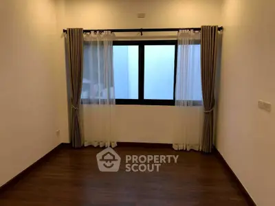 Spacious empty room with large window and elegant curtains, perfect for customization.