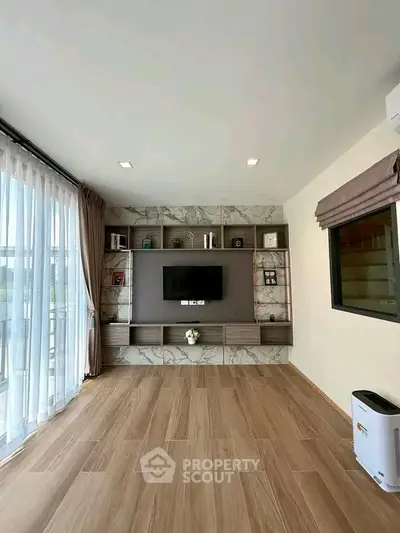 Spacious modern living room with elegant wood flooring and large window for natural light.
