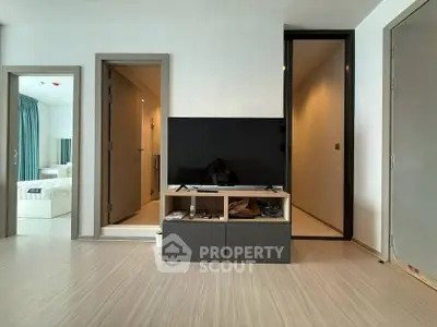 Modern living room with sleek TV stand and view into bedroom, showcasing minimalist design and open layout.