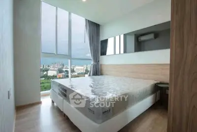 Modern bedroom with large window offering stunning city view, featuring sleek design and natural light.