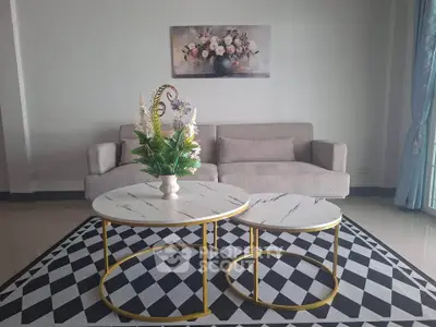Stylish living room with modern sofa and chic coffee tables on geometric rug.