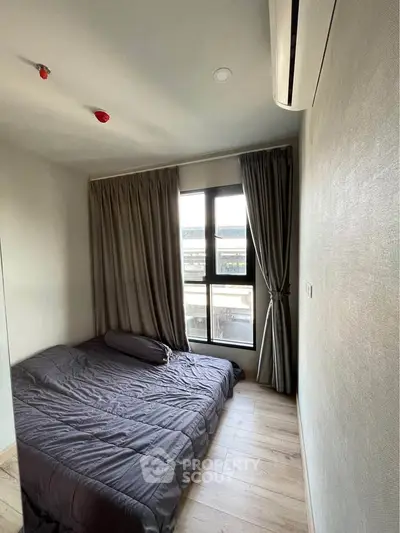 Cozy bedroom with modern decor and large window offering natural light.