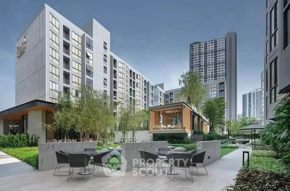 Modern apartment complex with lush garden and outdoor seating area, offering urban living with serene surroundings.