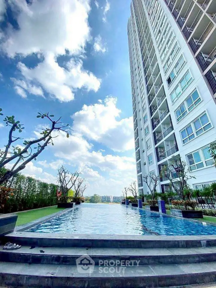Stunning high-rise building with luxurious pool and lush greenery under a bright blue sky.