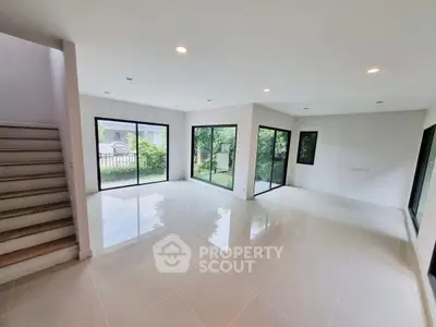 Spacious modern living room with large windows and glossy tile flooring