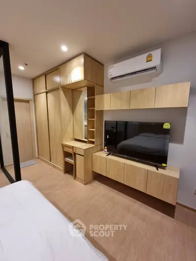 Modern bedroom with built-in wooden wardrobe and entertainment unit, featuring a sleek air conditioning system.