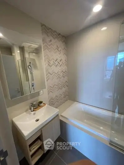 Modern bathroom with stylish tiles and built-in bathtub in contemporary apartment.