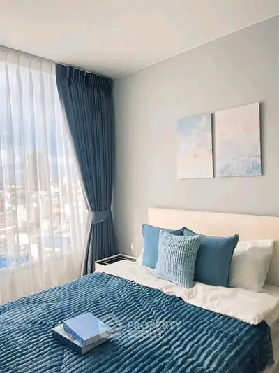 Modern bedroom with blue accents and large window offering city view