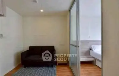 Modern living room with sliding door to bedroom, featuring a cozy sofa and wooden flooring.