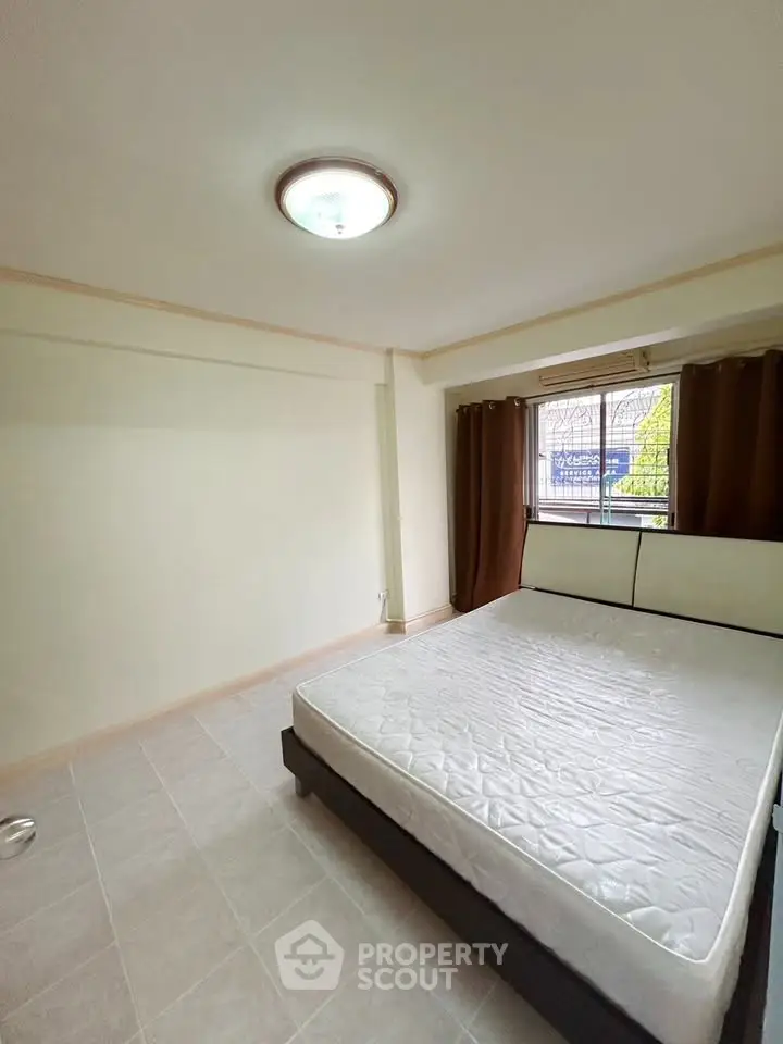 Spacious bedroom with large window and neutral decor, perfect for relaxation.