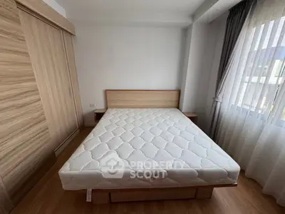 Spacious bedroom with wooden furniture and large window for natural light.