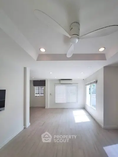 Spacious modern living room with ceiling fan and large windows for natural light.