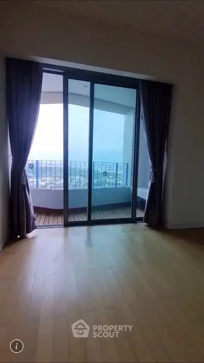 Spacious room with floor-to-ceiling windows leading to a balcony with stunning city views.