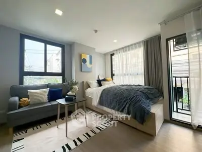 Modern bedroom with cozy decor and large windows offering natural light.