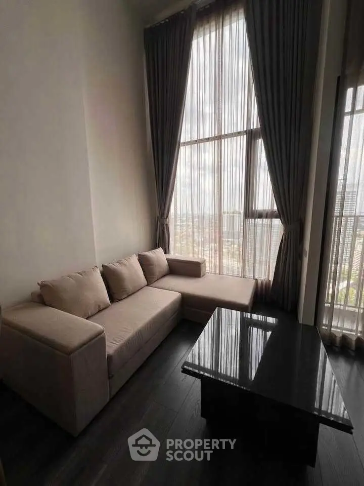 Spacious living room with high ceilings and large windows offering a stunning city view.