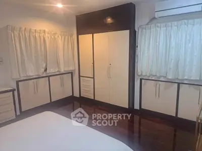 Spacious bedroom with elegant built-in wardrobes and polished wooden floors.