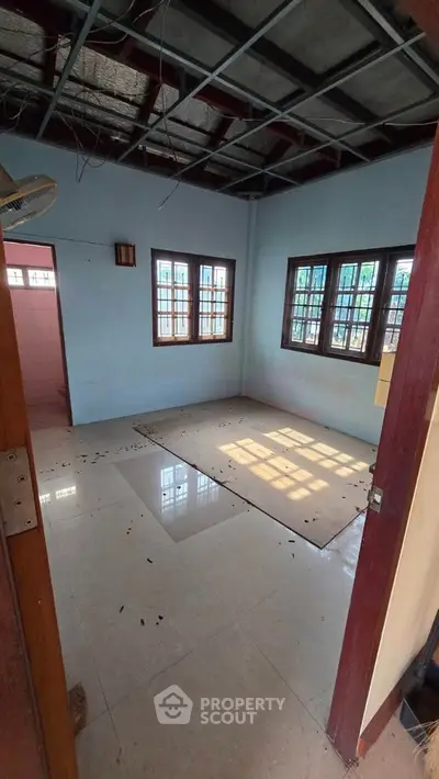 Spacious room with large windows and tiled floor, ideal for renovation.