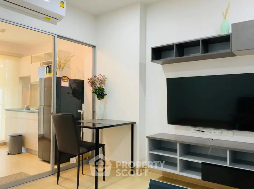 Modern living room seamlessly connected to a cozy kitchen area, featuring sleek furniture and a large flat-screen TV, perfect for urban living.