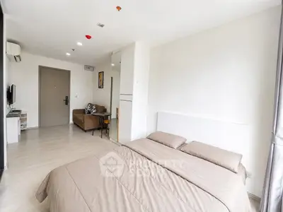 Spacious modern bedroom with cozy living area and neutral decor