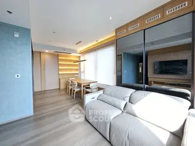 Modern living room with sleek design, featuring a large sofa, dining area, and wall-mounted TV.