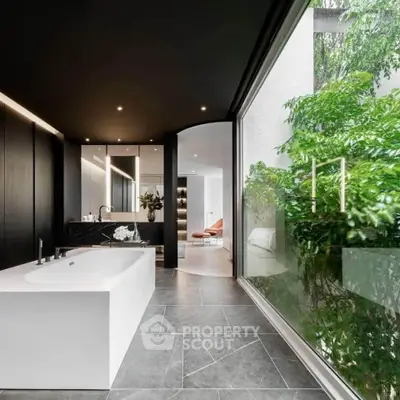 Luxurious modern bathroom with sleek design and large window overlooking lush greenery.