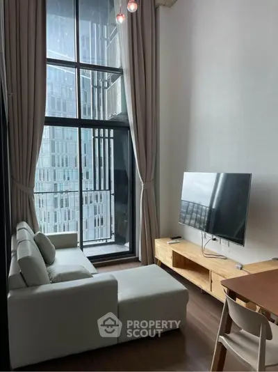 Modern living room with high ceilings and large windows offering city views.