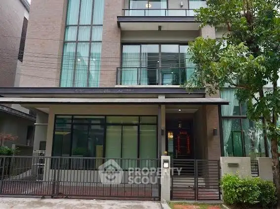 Modern multi-story building with large windows and gated entrance, ideal for urban living.