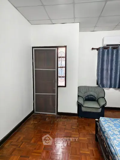 Cozy bedroom with wooden flooring and comfortable seating area.