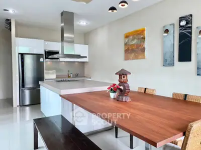 Modern kitchen with sleek design, featuring a large wooden dining table and contemporary art decor.