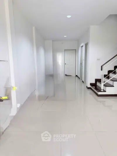 Spacious modern hallway with glossy tiled floors and staircase, ideal for contemporary living.