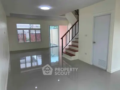 Spacious modern living room with glossy floors and staircase, ideal for family gatherings.