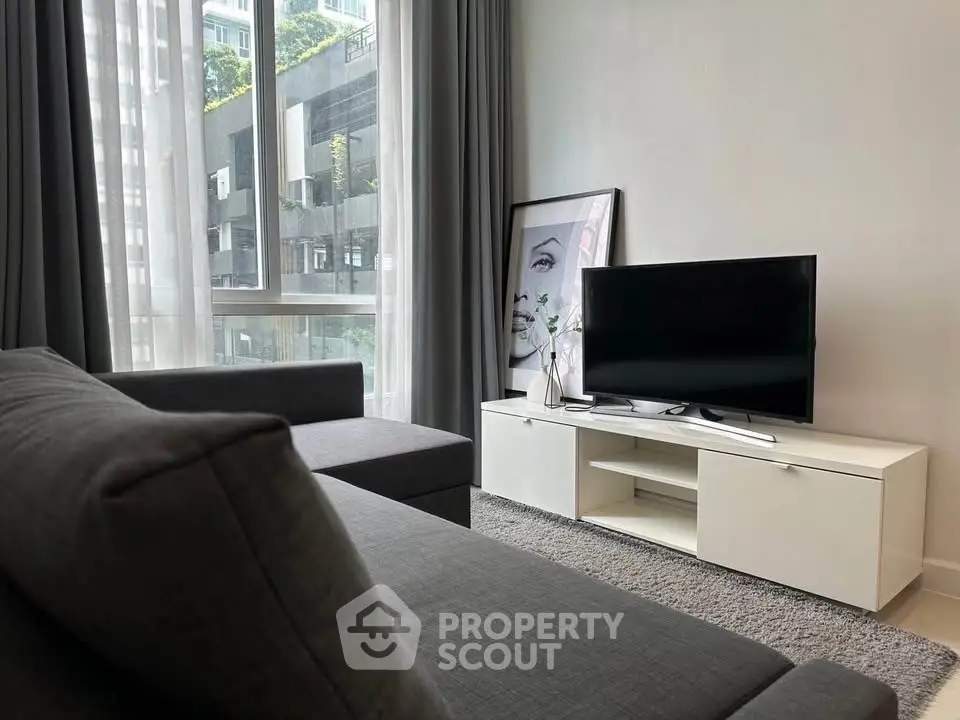 Modern living room with sleek furniture and large window offering natural light.