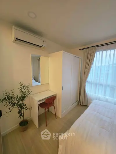 Cozy bedroom with air conditioning, wardrobe, and study desk, featuring natural light from large window.