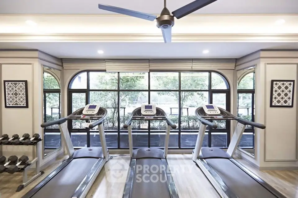 Luxurious gym with modern treadmills and elegant decor in upscale residential building.