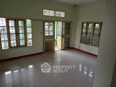 Spacious living room with large windows and natural light in a serene home setting.