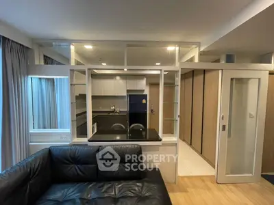 Modern living room with sleek black leather sofa and open kitchen layout