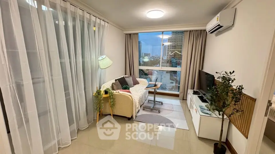 Cozy living room with modern decor and city view, featuring a comfortable sofa and entertainment unit.