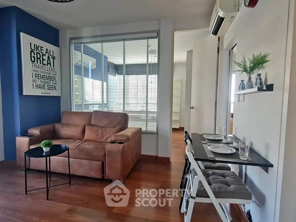 Modern living room with stylish decor and cozy seating area, featuring a wall-mounted air conditioner and wooden flooring.