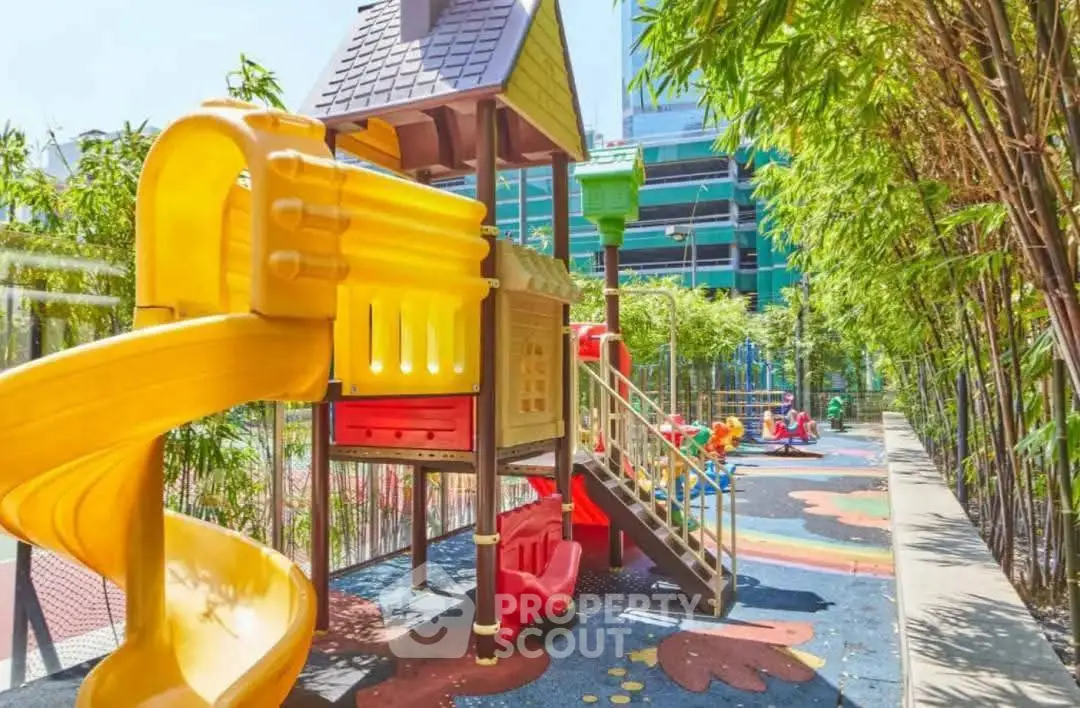 Vibrant playground area in modern residential complex with colorful slides and lush greenery.