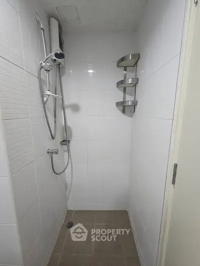 Compact bathroom shower area with modern fixtures and white tiled walls.