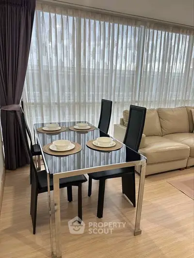 Modern living room with sleek dining set and cozy sofa, featuring floor-to-ceiling windows for natural light.