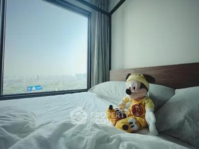 Cozy bedroom with large window offering stunning city view, featuring plush bedding and charming decor.