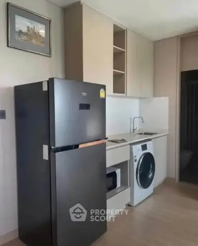 Modern kitchen with sleek appliances including fridge and washing machine, compact and efficient design.