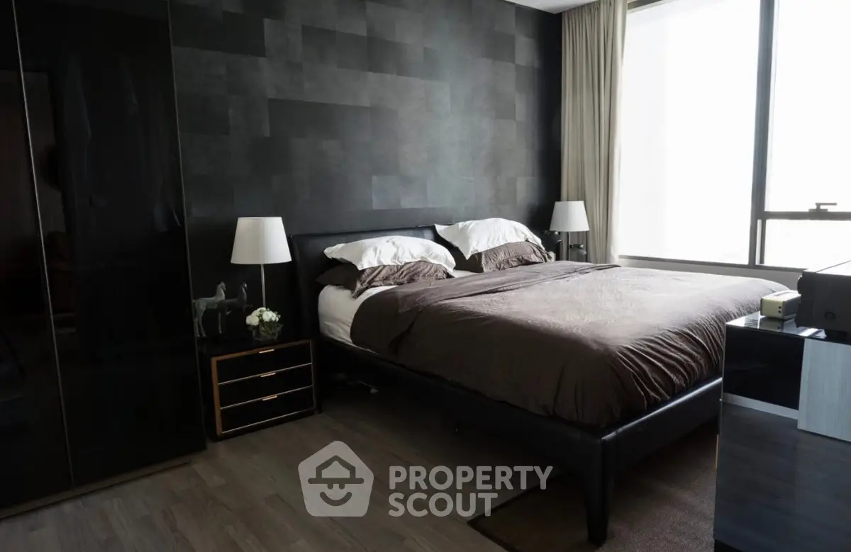 Luxurious modern bedroom with sleek black accents and large window view.