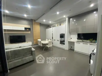 Modern open-layout living room with sleek kitchen and dining area, featuring contemporary design and ample lighting.