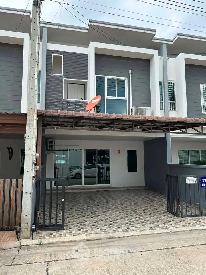 Modern townhouse exterior with parking space and satellite dish in urban setting.