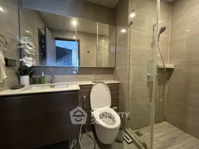 Modern bathroom with glass shower and sleek vanity in contemporary home.